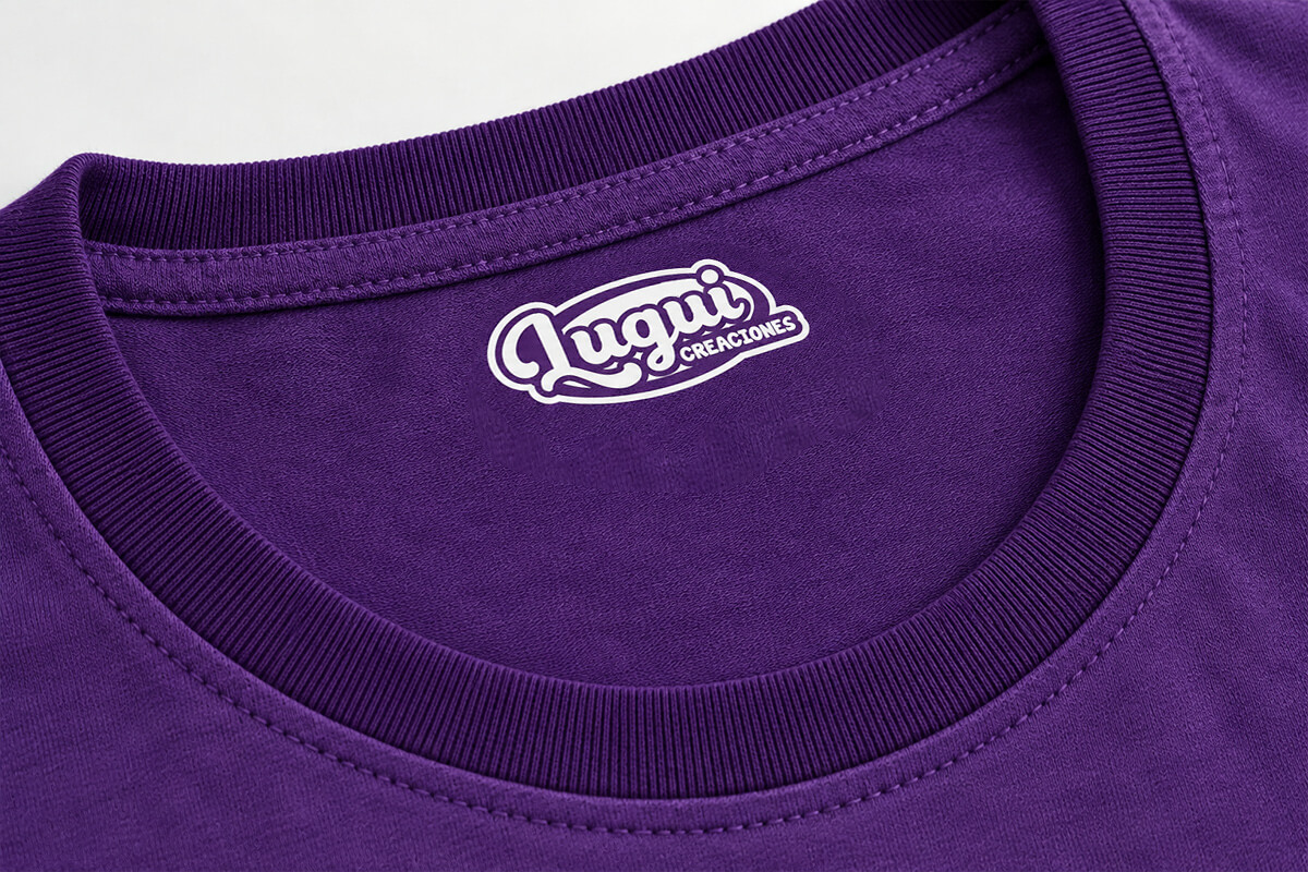 Aplicación monocromática del logotipo de Lugui Creaciones estampada en el cuello de una camiseta gris